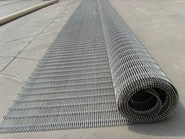 A piece of architectural metal mesh rolled up on the ground