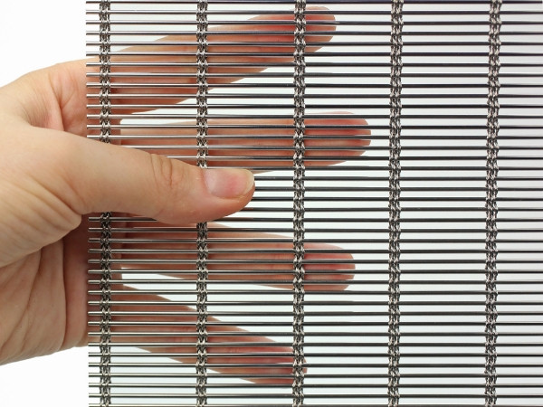 A hand is holding a piece of stainless steel architectural metal mesh