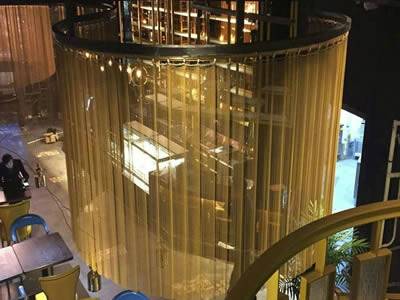 Brass flexible mesh curtain is installed in the ceiling of restaurant.