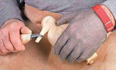 A carver is engraving birds with graver and his left hand is wearing chainmail gloves.