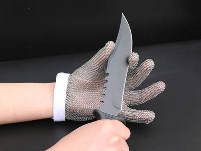 A chainmail glove with a white wrist strap is being carried out anti-cutting test by using a knife.