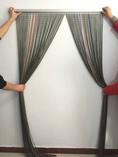 A chain link curtain is fastened by four hands.