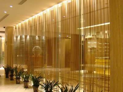 Brass mesh coil curtain is installed outside the glass wall in the luxury building.