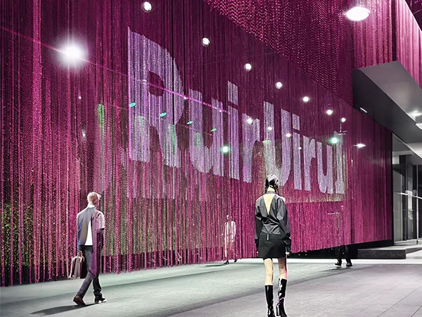 The fashion show stage is partitioned with a metal chain link curtain.