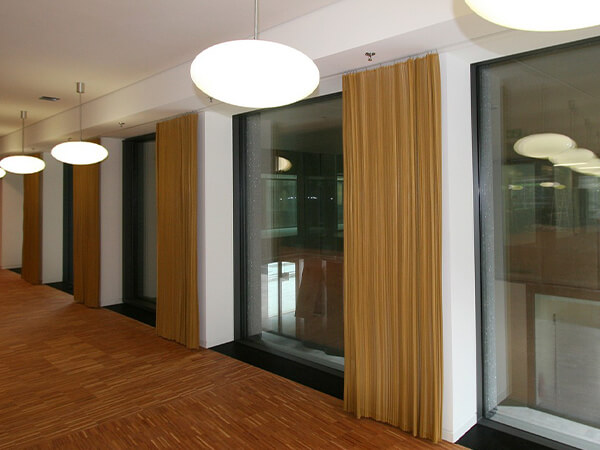 Museum walls with floor-to-ceiling glass that uses gold metallic curtains.