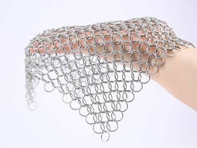 A stainless steel chainmail baking cover covering a hand.