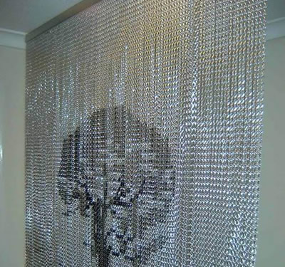 Aluminum chain link curtain with a tree design defines spacious living room